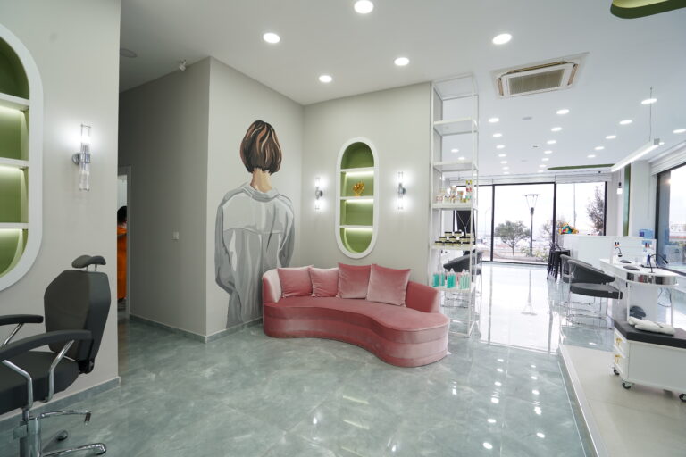 Eleganter Wartebereich im Bahar Babacan Beauty Center mit rosa Designer-Sofa und moderner Studioeinrichtung.